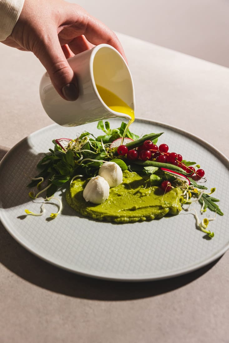 Plated burrata salad being dressed at the table