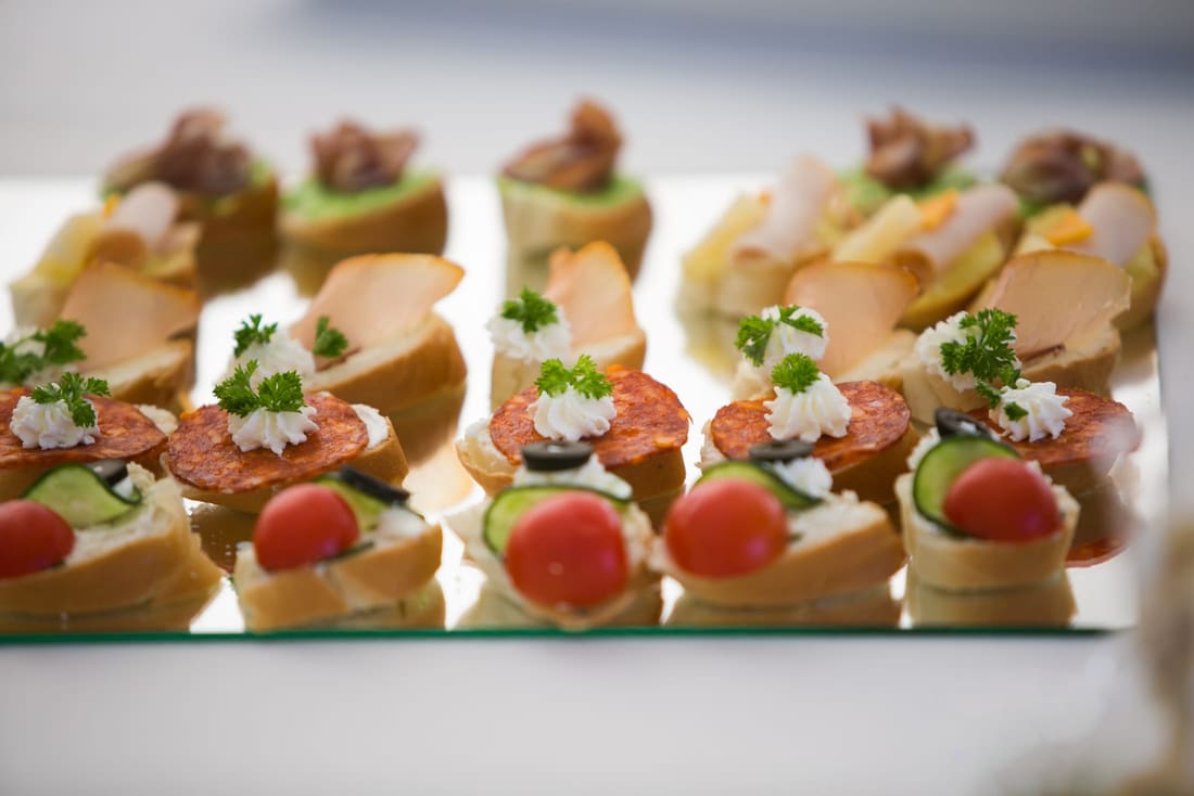 Row of canapés topped with cream and herbs